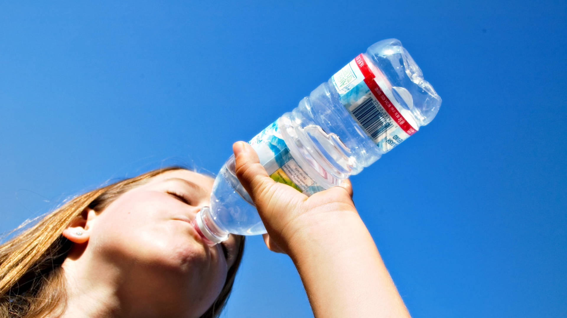 Vrou drink water uit bottel Muurpapier