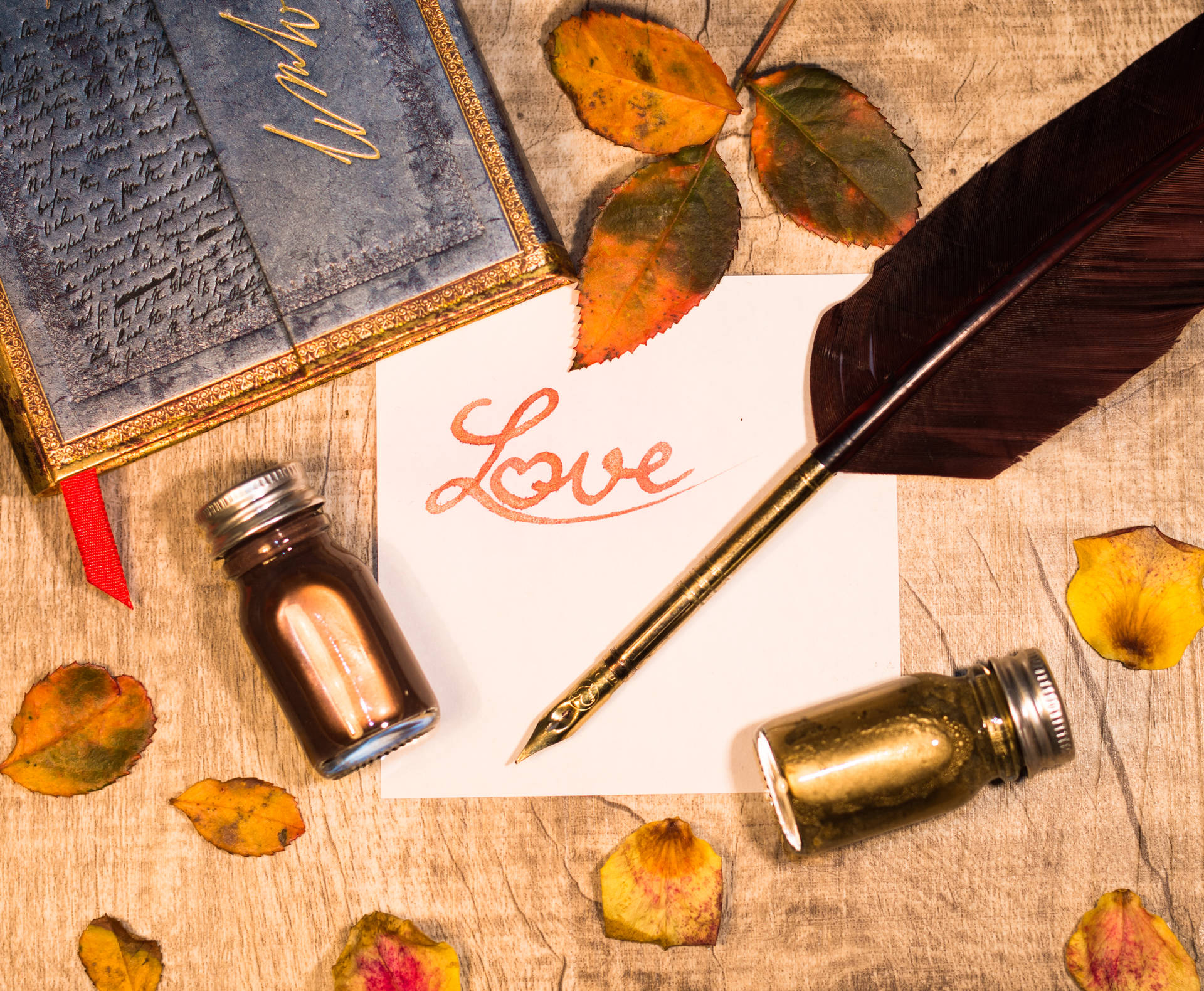 Oranje inskripsie "Liefde" geskryf op 'n wit stuk papier met veerpen en bottels ink op 'n houttafel. Liefdesbrief vir Valentynsdag.