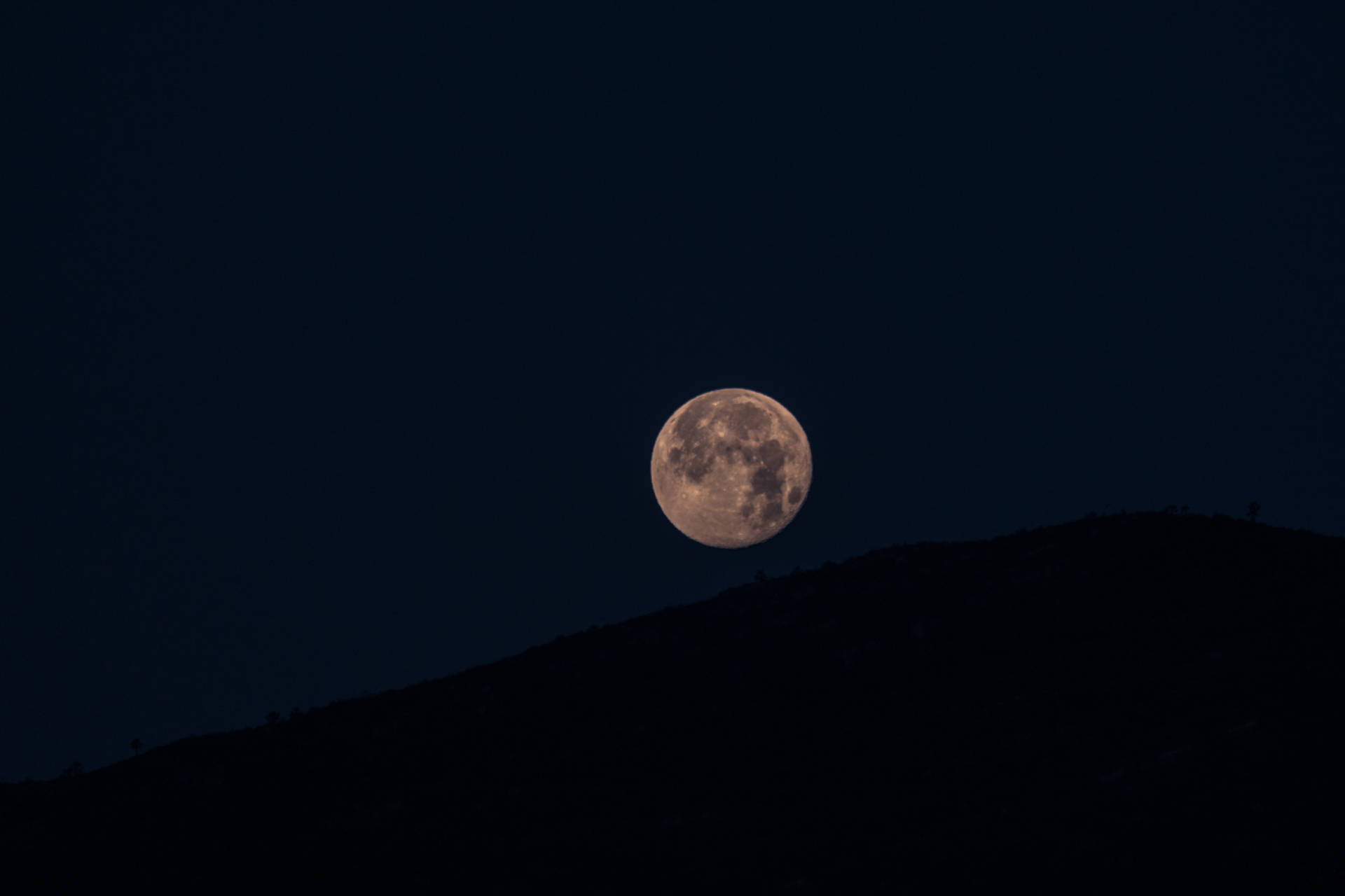 Volmaan wat helder skyn bo-op die heuwels. Minimalistiese foto van maan en hooglande.