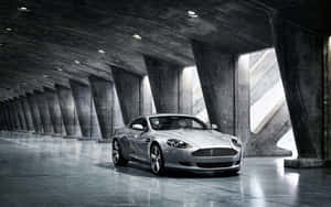Aston Martin DB9 wat deur 'n Skilderagtige Stadsbeeld Kruis — Steam Deck OLED Muurpapier