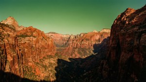 Red rock canyon walls contrast with a vivid green sky above. — Groen lug Muurpapier
