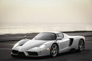 Flitse silwer Ferrari Enzo met see agtergrond.