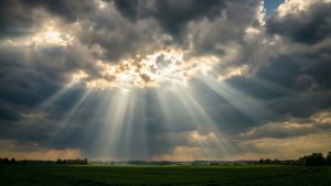 Sonstrale wat deur wolke breek oor 'n groen veld. — Luguitsig Muurpapier