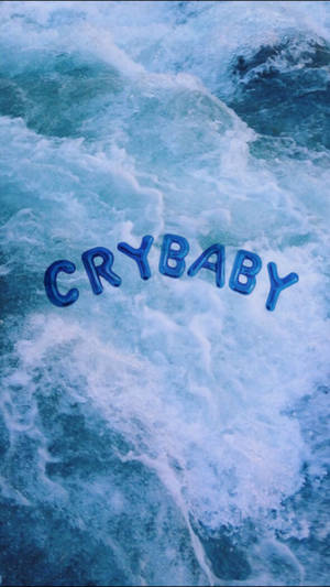 Koel blou estetiese muurpapier van groot ballonletters wat 'Crybaby' op 'n blou oseaan of see laat dryf.
