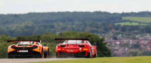 Jaermotor Ferrari en McLaren op die padmuurpapier.