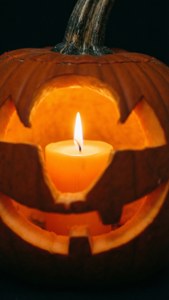 Nabyfoto van 'n kers in 'n pampoen vir 'n intieme Halloween-estetika. — Halloween estetiek Muurpapier