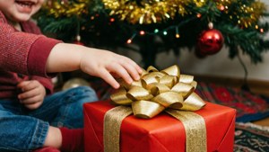 Kind se hand wat na rooi geskenk onder Kersboom reik. — Kersgeskenke Muurpapier