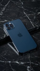 iPhone 17 in middernagblou op marmer, minimalistiese ateljeefoto.
