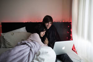 paar op bed wat MacBook Air gebruik langs venster met wit gordyn — MacBook Pro Muurpapier