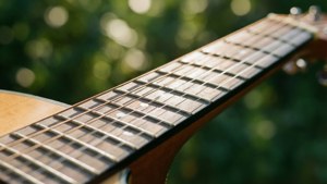 Nabyfoto van kitaarsnare met groen bokeh, warm sonlig. — Musiek estetika Muurpapier