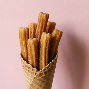 Gestapelde churros in 'n keël teen 'n pienk agtergrond. — Pixel Watch 3 Muurpapier