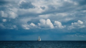 Stemmingvolle bewolkte lug oor die see met 'n seilboot, rustige maritieme muurpapier. — Luguitsig Muurpapier