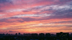 'n Kleurvolle dagbreekhemel bo 'n stad se skyline-silhoeët. — Luguitsig Muurpapier